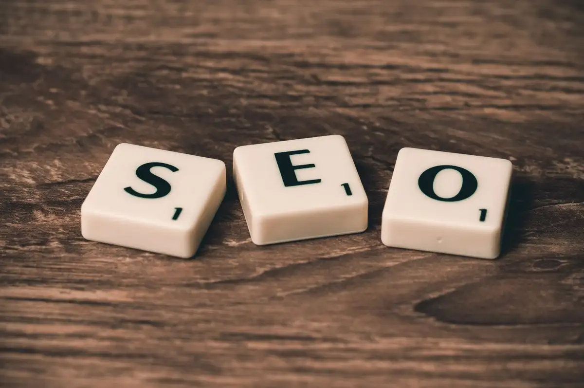 Peças de letras formando a palavra SEO sobre mesa de madeira